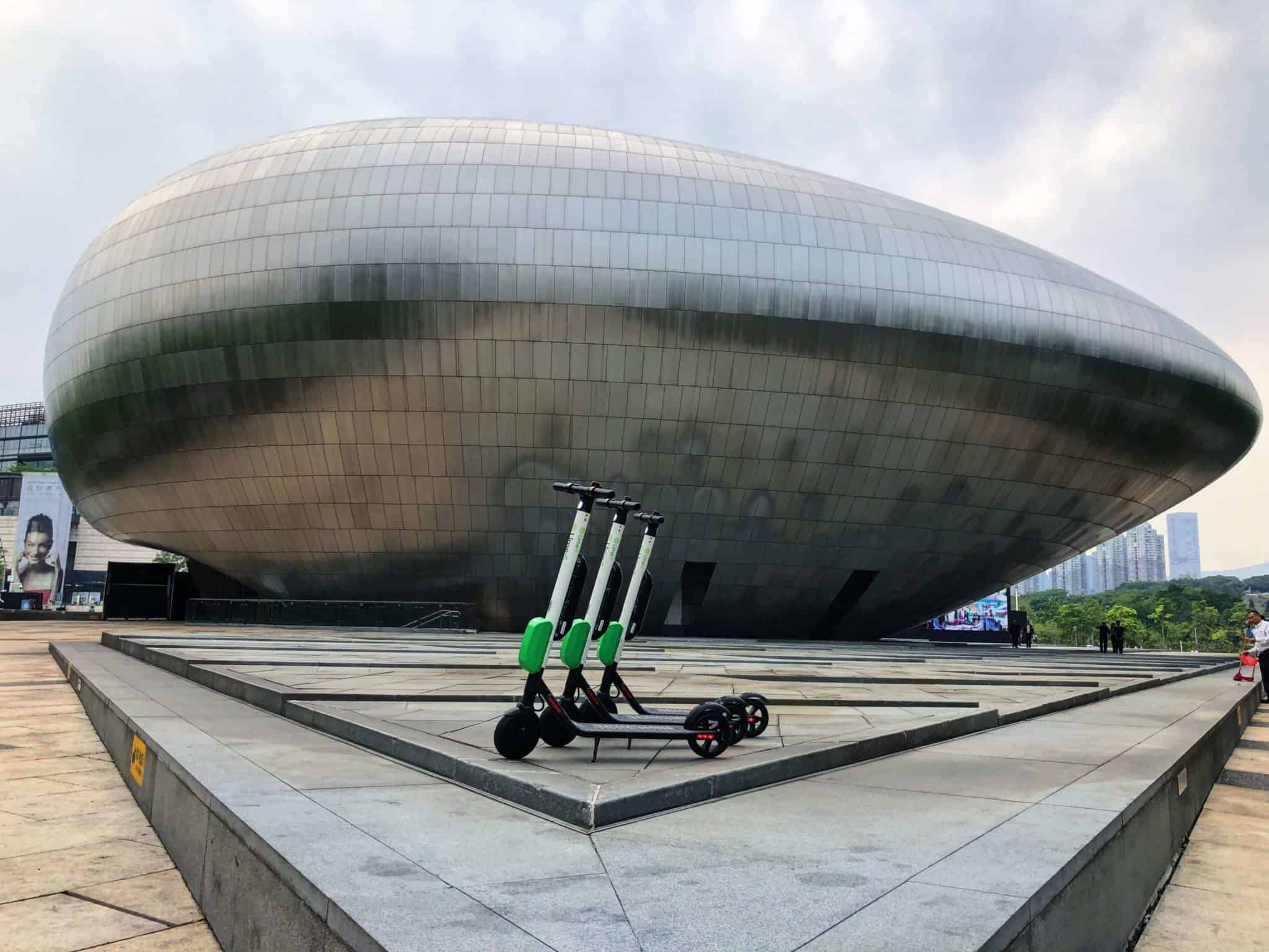3 lime scooters in front of a sculpture