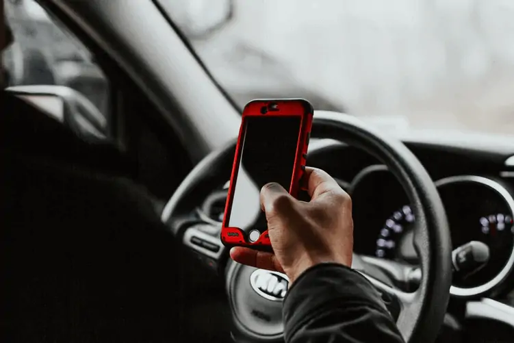 Person looking on iPhone in driver's seat