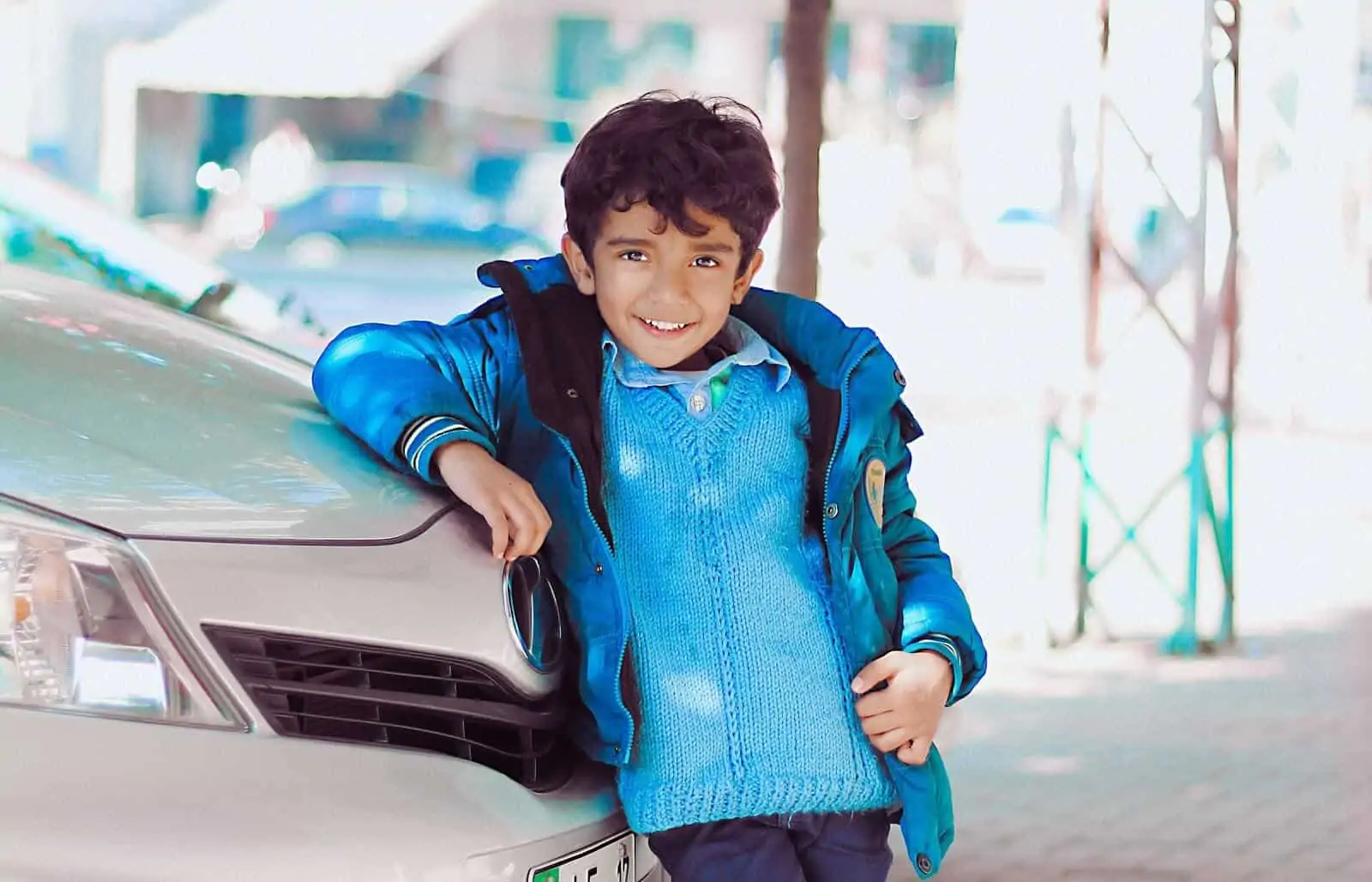Little boy leans against car