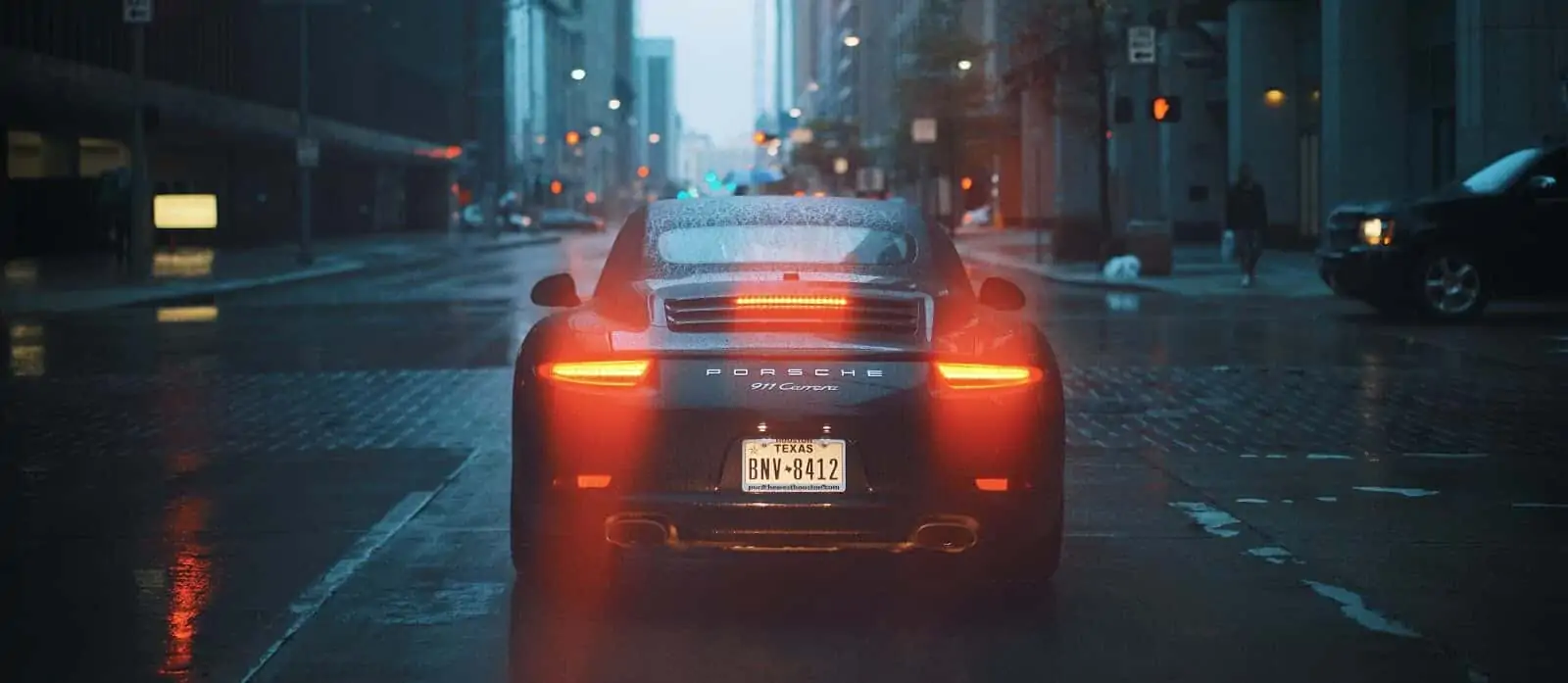 Porche with tail lights glowing on city street
