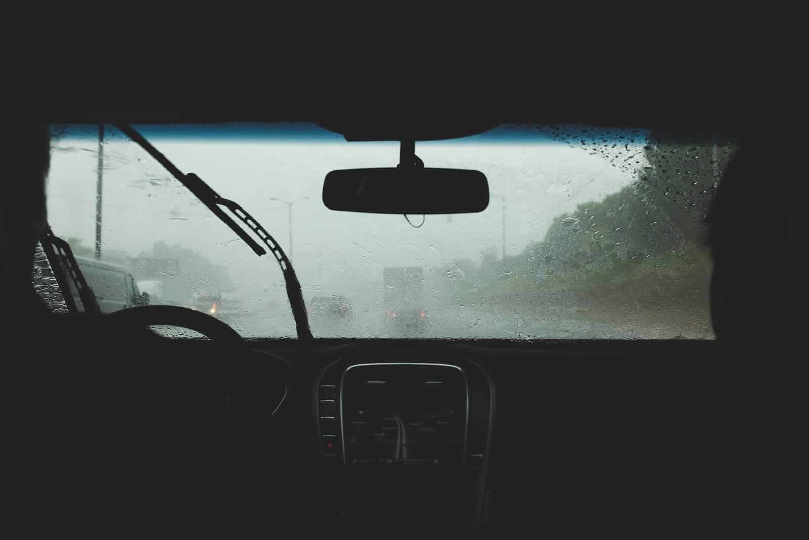 View of rainy windshield from the backseat on a cloudy day