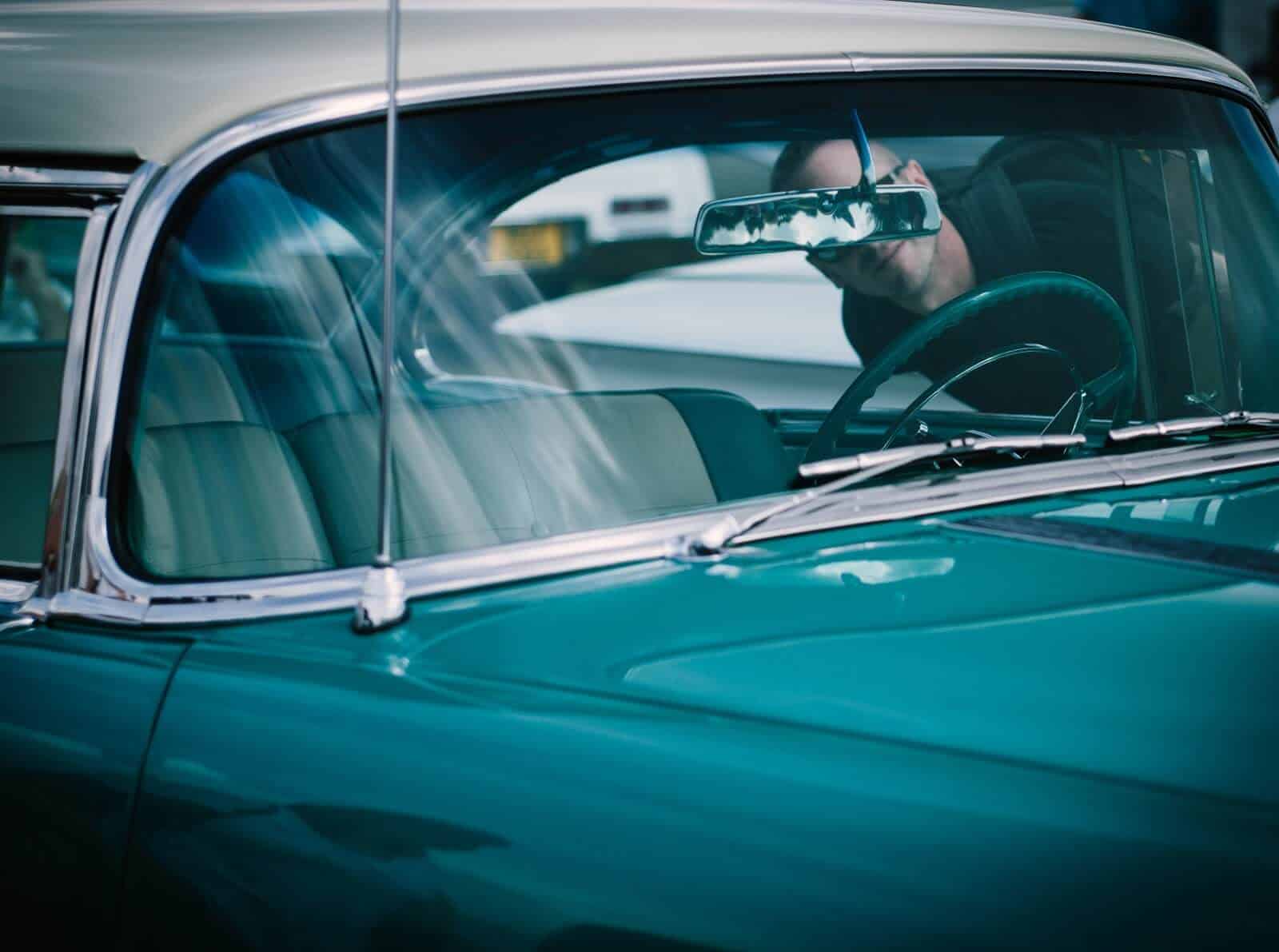 Man peering into vintage car 