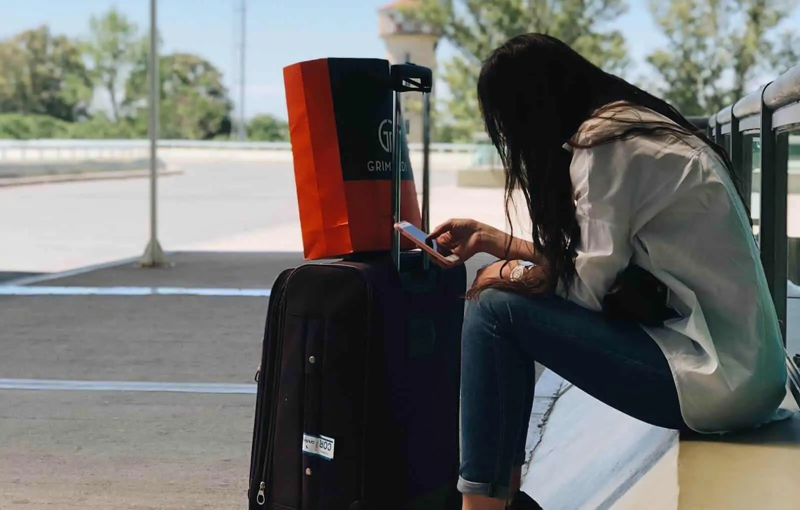 Woman waiting outside airport with suitcase