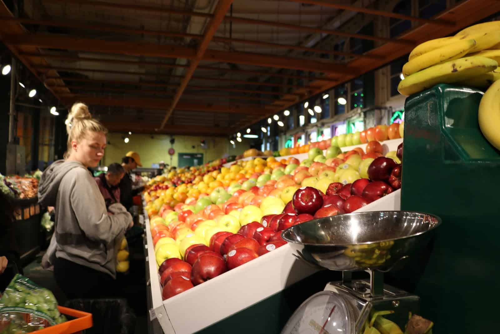 Woman looks at apples at grocery store