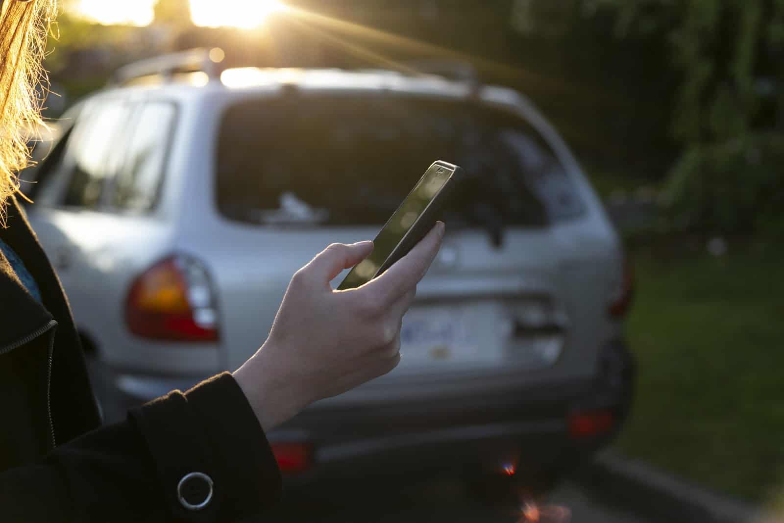 Car share: A woman uses her phone outside of an SUV