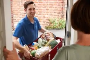 Smiling man delivers groceries to a home