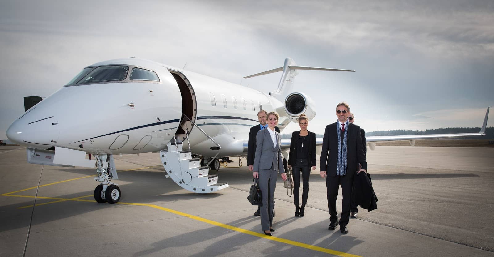 Empty leg flights: A private plane on the tarmac with business people standing in front of it
