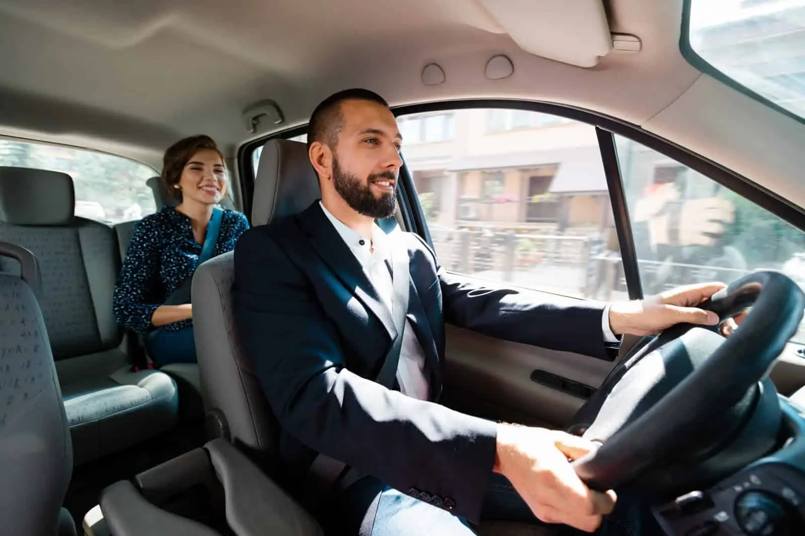 Drive for Lyft: A well-dressed man in the driver's seat with a passenger in the seat behind him