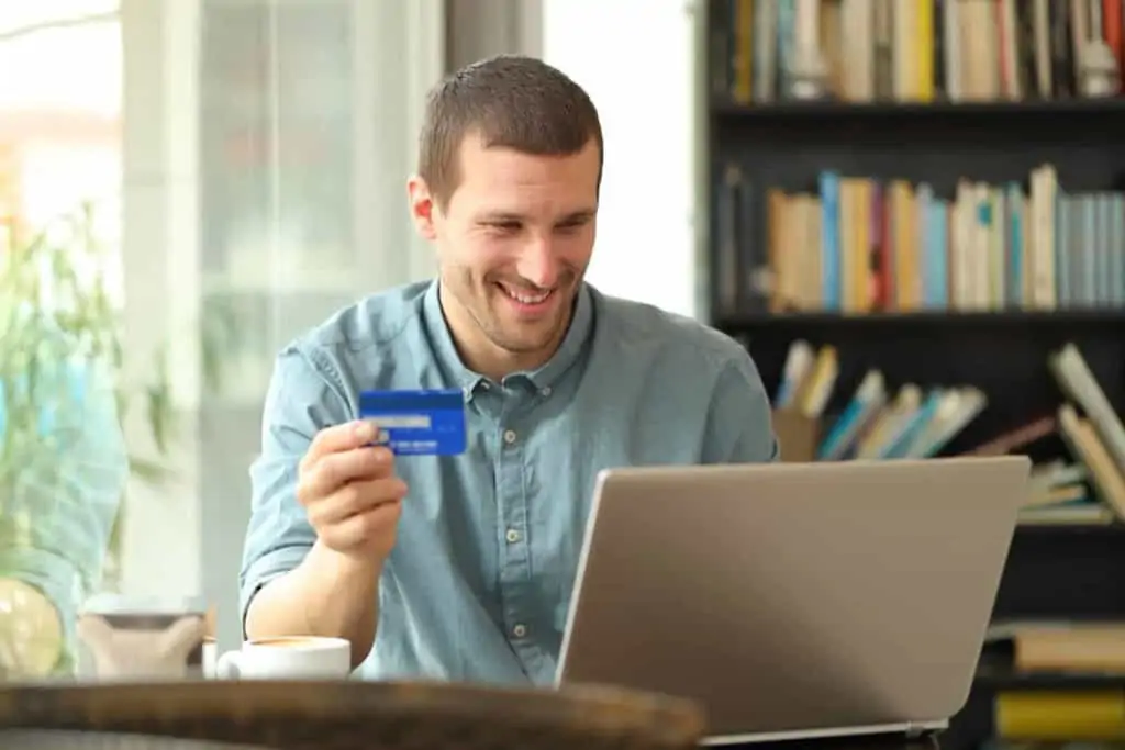 Man holding credit card while typing on laptop