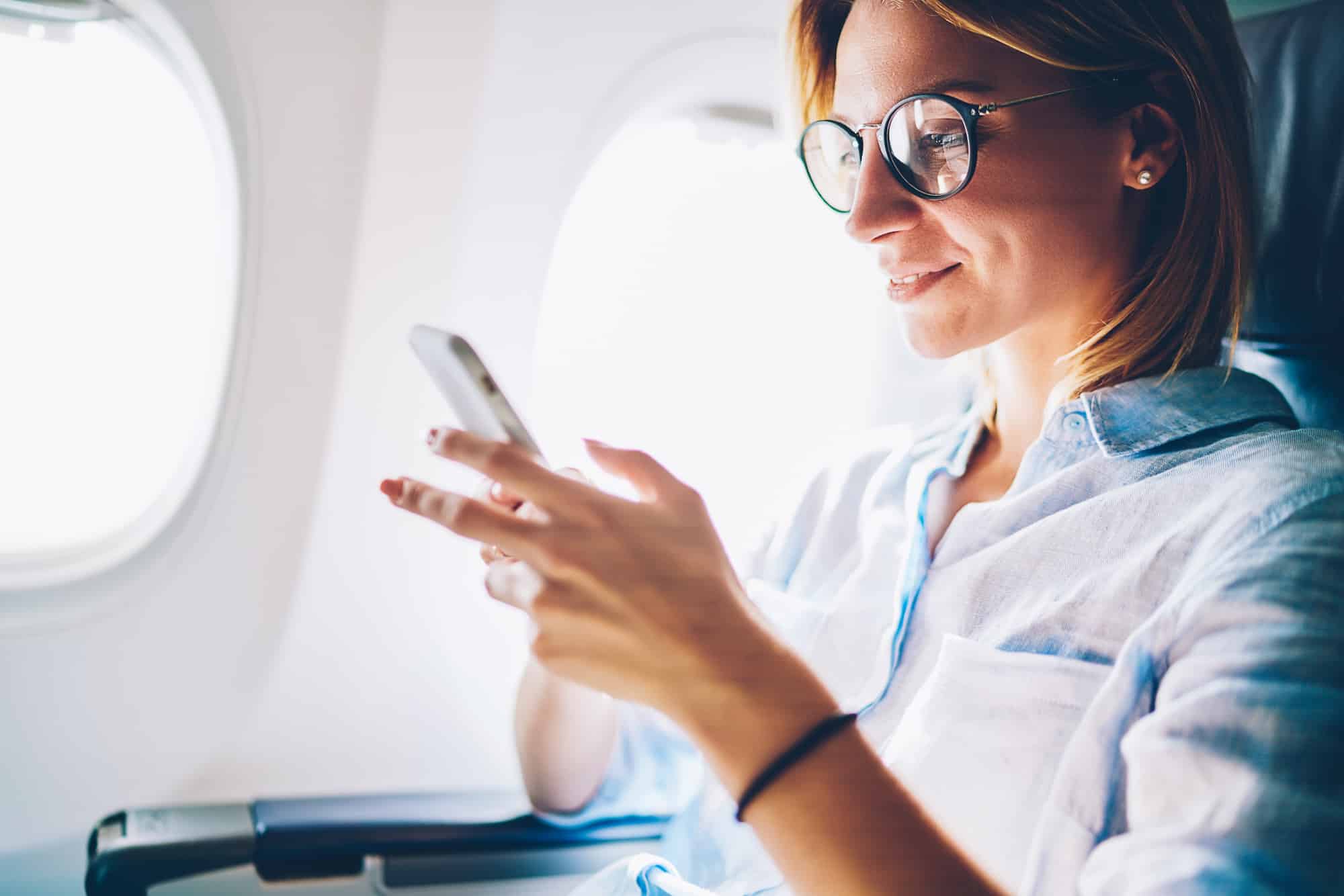 Woman on airplane looking at cell phone