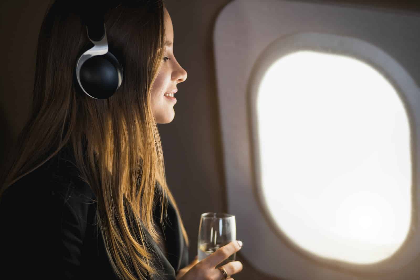A woman listening to music and sipping champagne on a VistaJet private plane