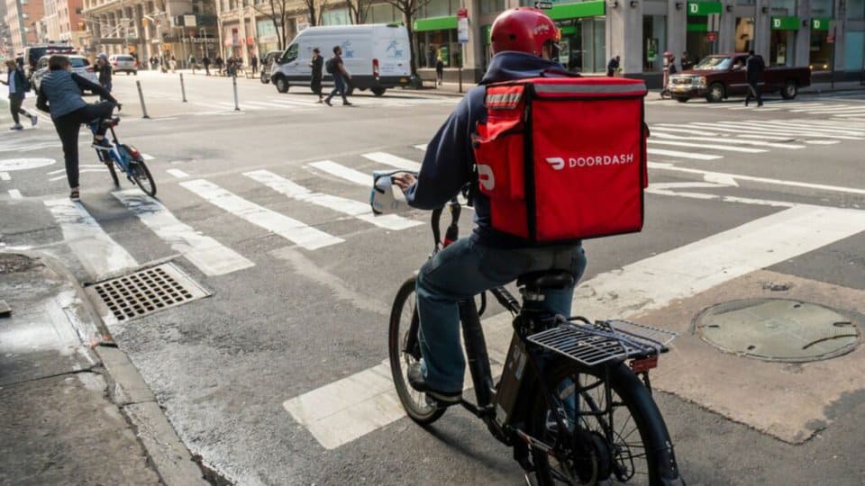 photo of a man riding a bike with a doordash hot bag on his back - header graphic for doordash bike delivery post on ridester.com