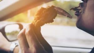 header image for doordash stole my food image on ridester showing somebody eating chicken while driving a car