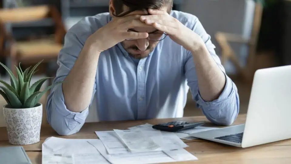 image showing a man looking stressed and looking down at paper on his desk - risks and considerations of loans for uber drivers post