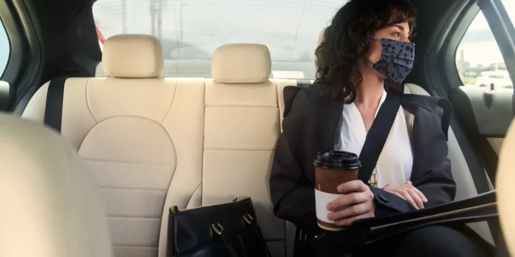 stock image showing a business woman in an Uber for business vehicle holding a coffee